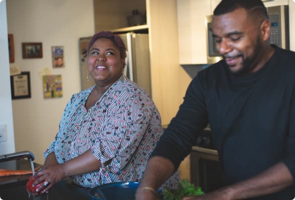Um casal realizando atividades na cozinha de bem com a vida